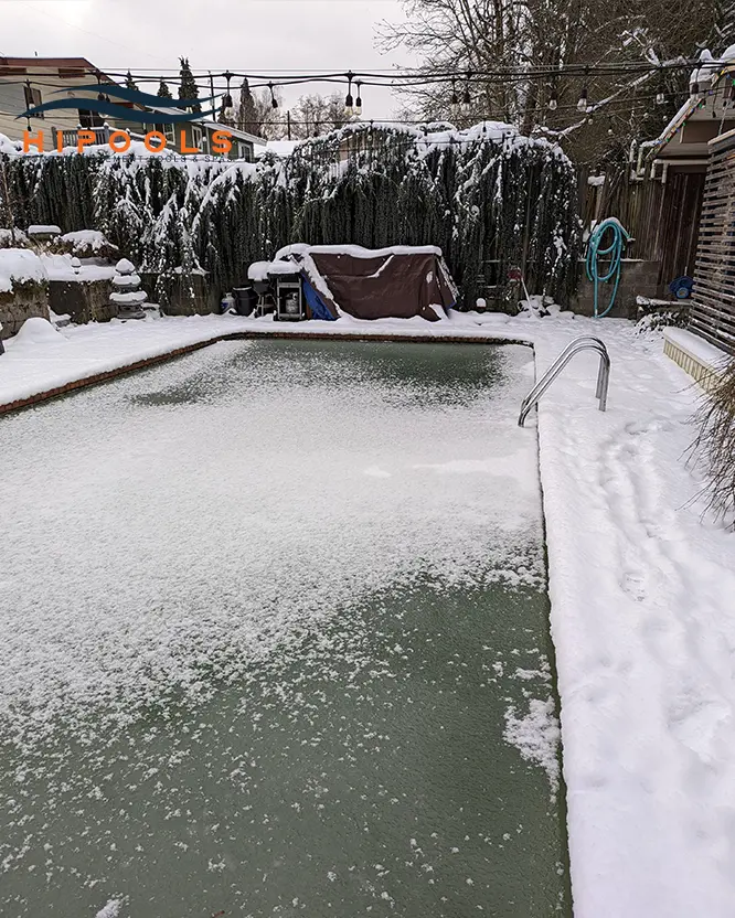 A covered swimming pool surrounded by snow, showcasing winterization techniques