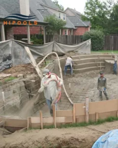 Workers constructing an inground swimming pool, showcasing heavy machinery and building materials